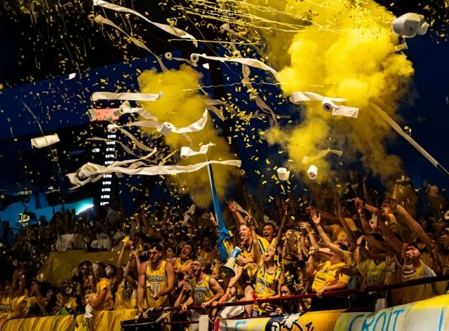 Trois hommes sautent simultan&eacute;ment avec des expressions de joie et d'enthousiasme, bras lev&eacute;s en signe de victoire