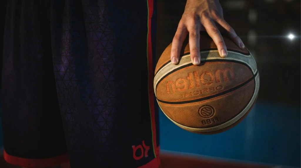 Un homme d'affaires en costume sombre et cravate bordeaux jongle avec un ballon de football dans un bureau moderne